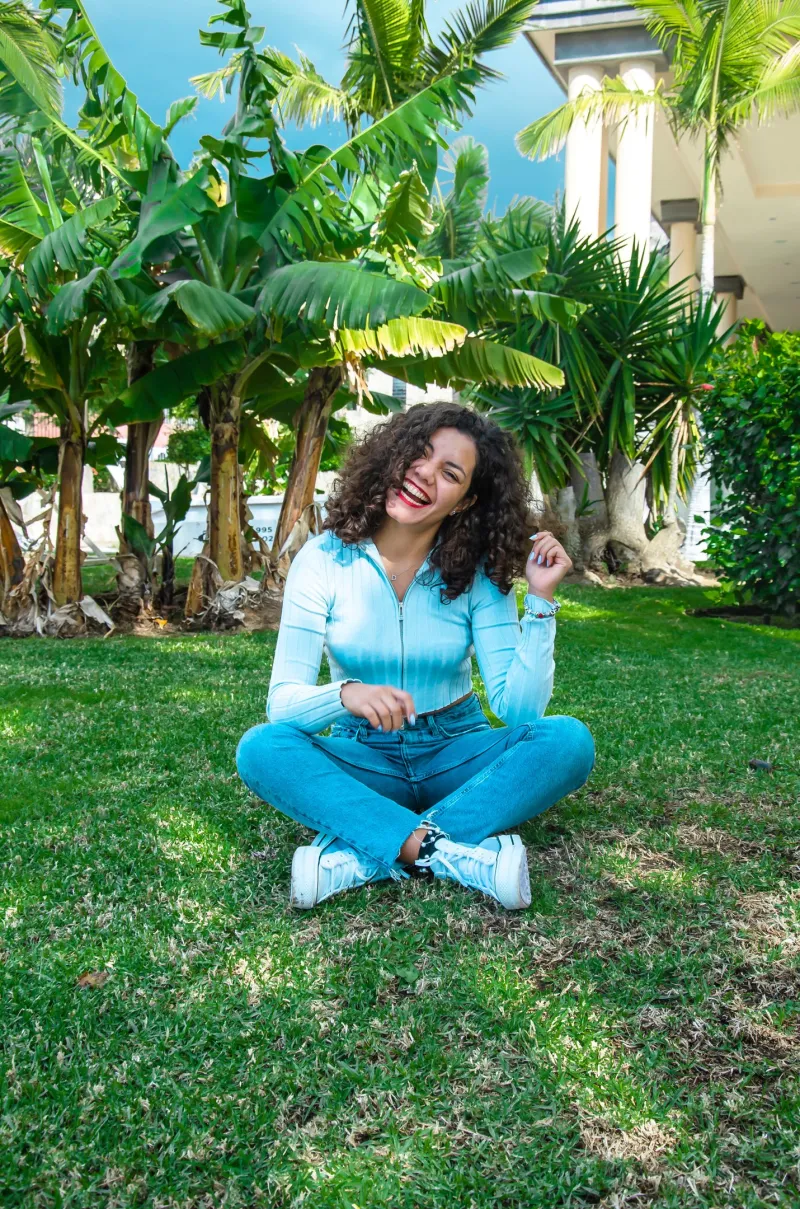 Andrea sentada en el césped de un jardín tropical
